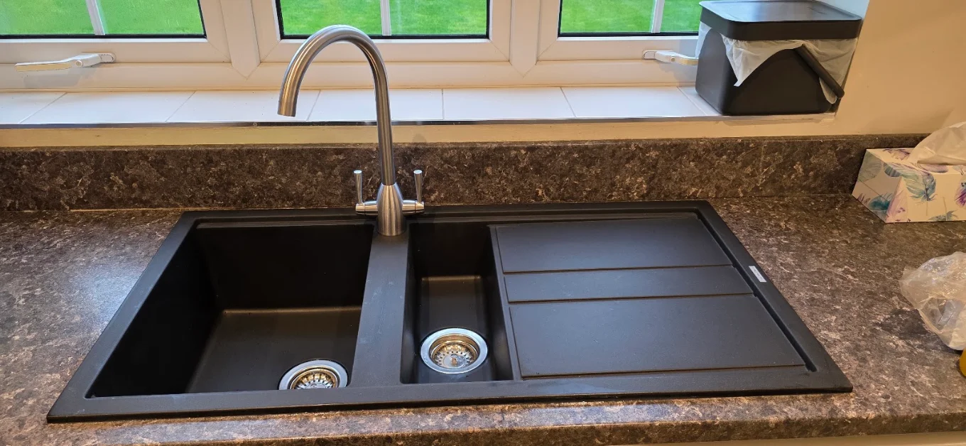 Black kitchen sink with a chrome mixer tap, from Blackmore Plumbing’s completed work